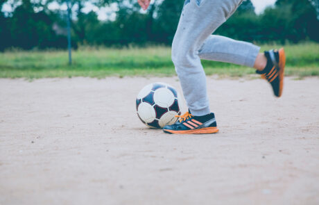 Bild på benen av ett barn som spelar fotboll. Barnet är på väg att sparka på fotbollen.