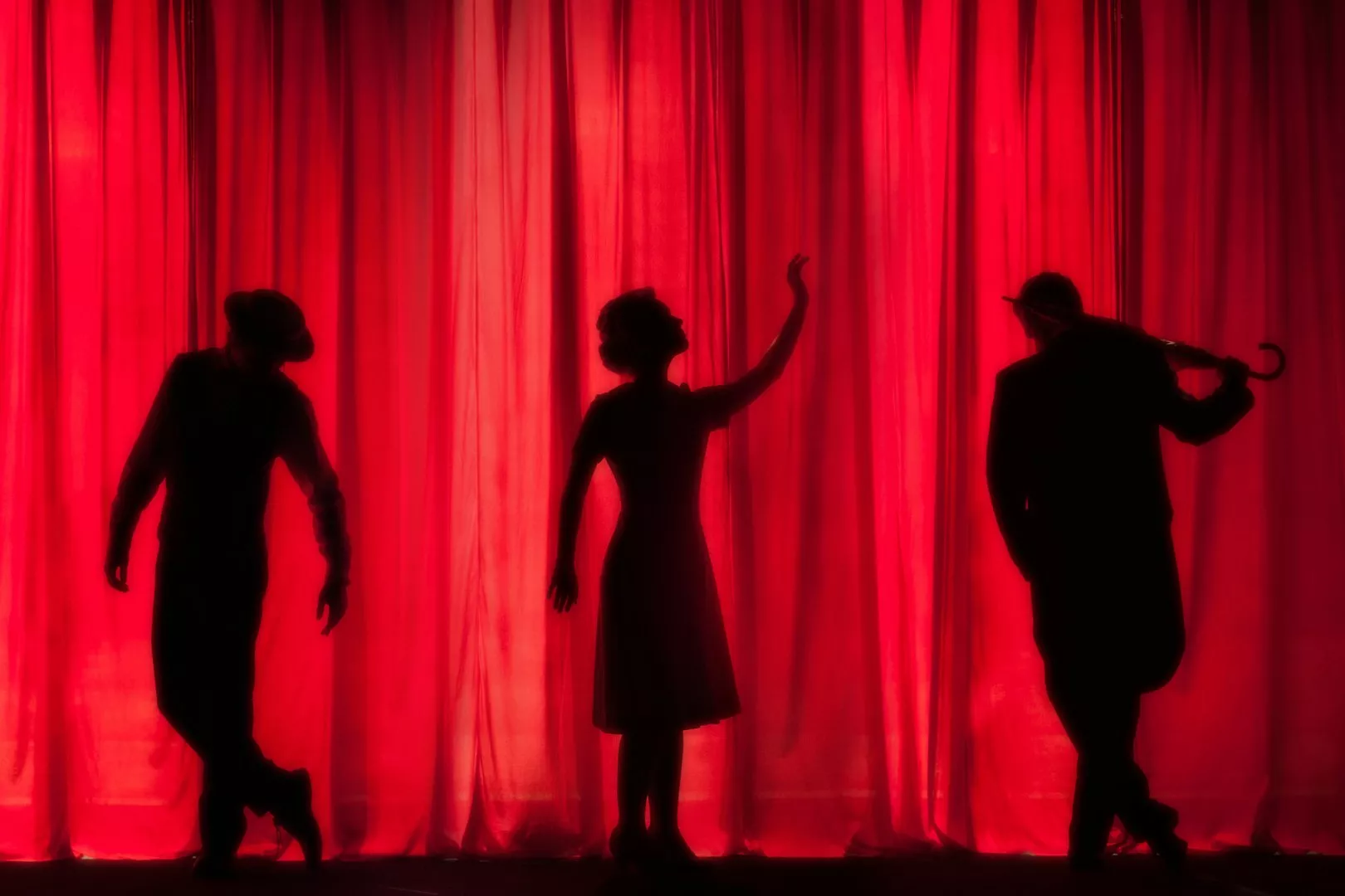 drama silhouettes of three people on a red curtain