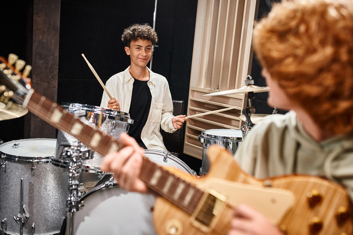 Teenagers perform together in a music studio, expressing creativity through band practice